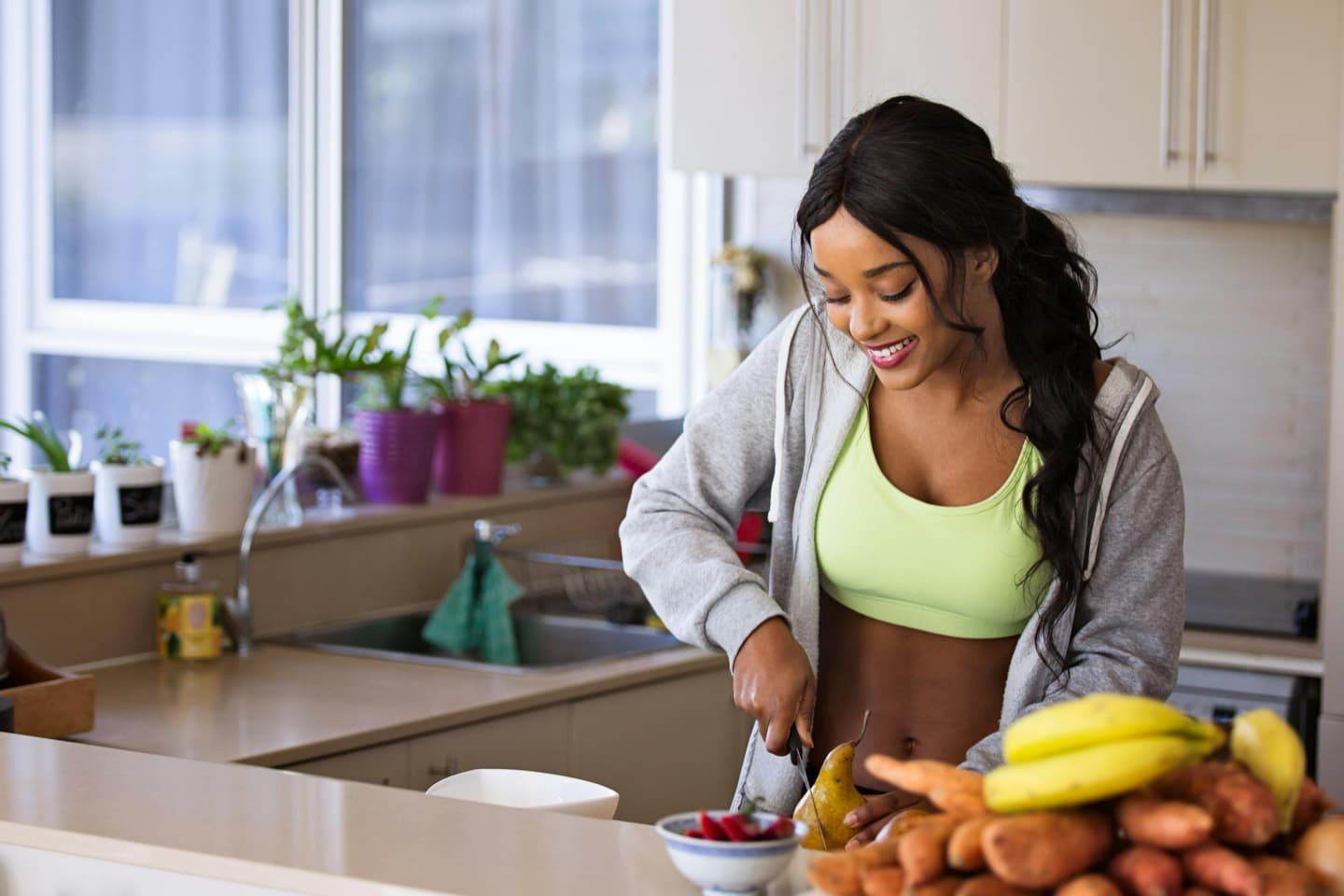 Woman preparing a healthy meal in her kitchen, fresh fruit and vegetables on the counter